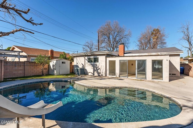 view of pool with a water slide, a storage unit, and a patio