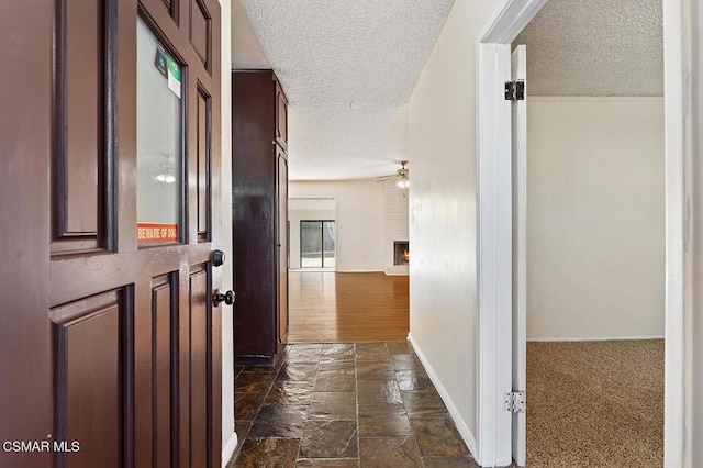 hallway with a textured ceiling and dark colored carpet