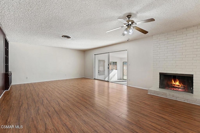 unfurnished living room with ceiling fan, hardwood / wood-style floors, a textured ceiling, and a fireplace