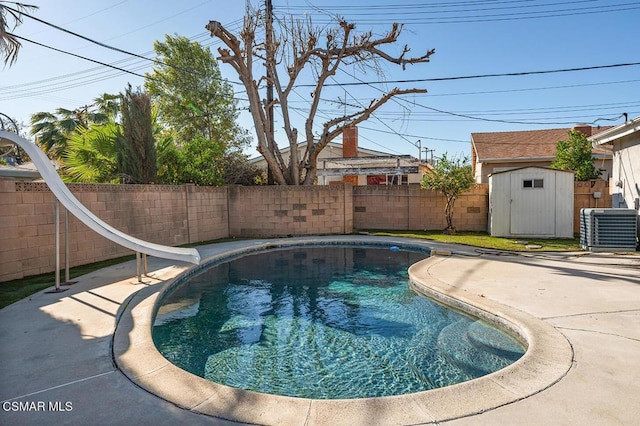 view of swimming pool featuring central AC unit, a storage unit, a patio area, and a water slide