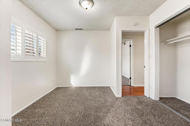 unfurnished bedroom with a textured ceiling, a closet, and dark carpet