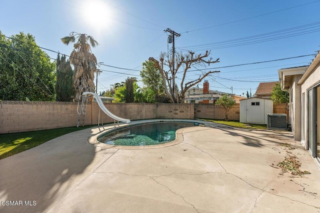 view of swimming pool with a patio, a water slide, a storage unit, and cooling unit