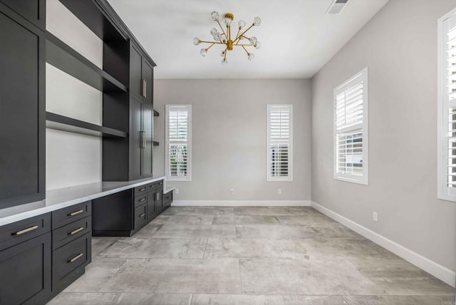 unfurnished office featuring an inviting chandelier and built in desk