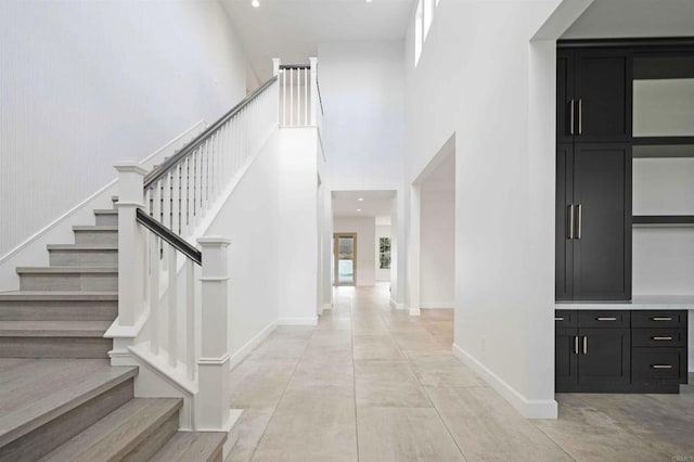 stairway featuring a high ceiling, concrete floors, and plenty of natural light