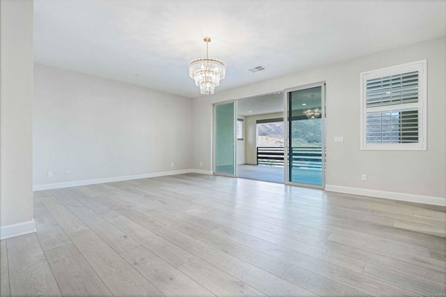 empty room with an inviting chandelier and light hardwood / wood-style flooring