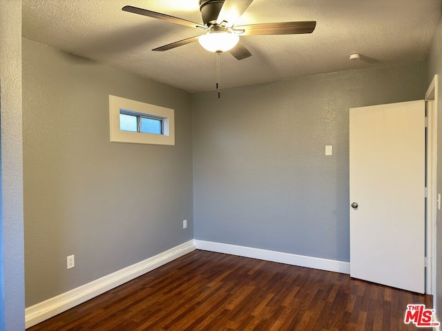 empty room featuring ceiling fan, dark hardwood / wood-style floors, and a textured ceiling