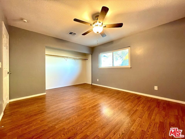 unfurnished bedroom with ceiling fan, wood-type flooring, and a textured ceiling