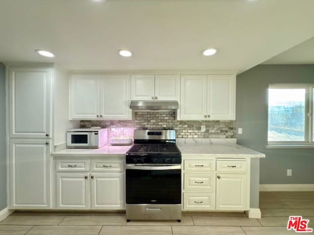 kitchen with light stone countertops, white cabinets, and stainless steel gas range oven