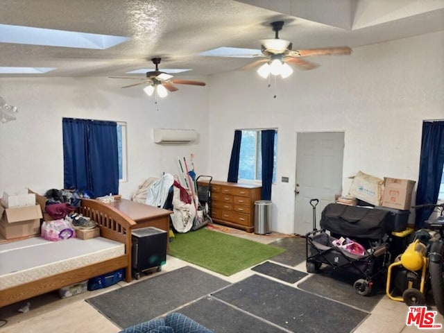 bedroom featuring ceiling fan, vaulted ceiling with skylight, a textured ceiling, and a wall mounted AC