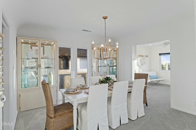 carpeted dining room featuring a notable chandelier