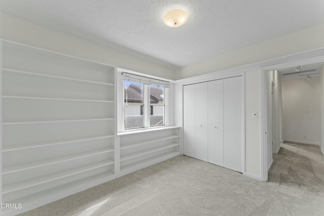 unfurnished bedroom with light colored carpet, a textured ceiling, and a closet