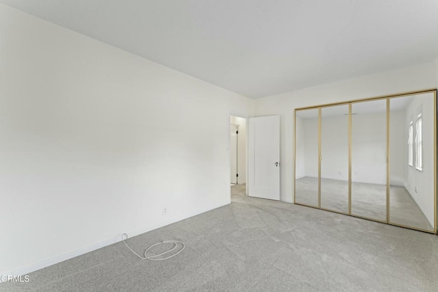 unfurnished bedroom featuring light carpet and a closet