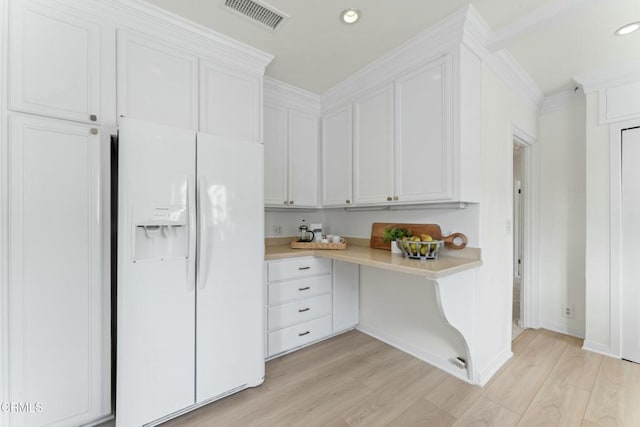 kitchen with light hardwood / wood-style flooring, white cabinetry, built in desk, white refrigerator with ice dispenser, and ornamental molding