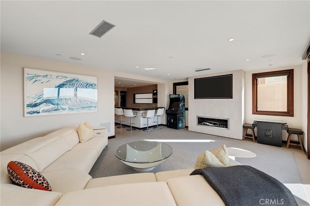 living room with carpet floors, a glass covered fireplace, visible vents, and recessed lighting