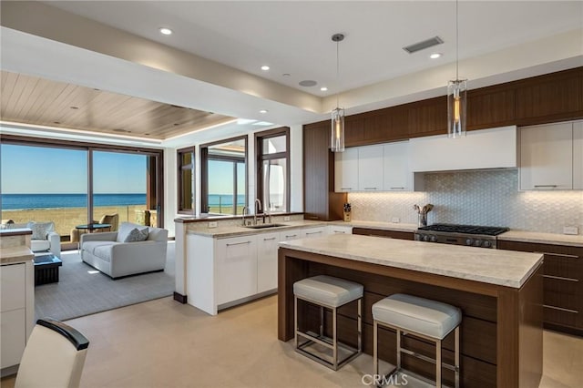 kitchen with modern cabinets, backsplash, visible vents, and a center island