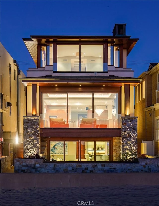 back of house at night with stone siding