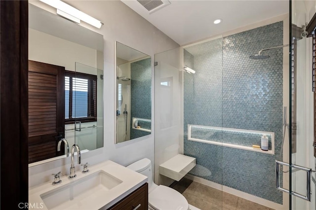 full bath with visible vents, toilet, a tile shower, vanity, and tile patterned floors