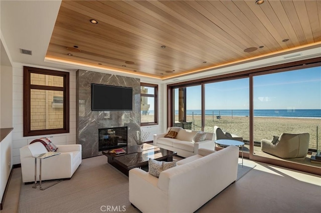 living area with visible vents, a raised ceiling, a high end fireplace, wooden ceiling, and recessed lighting