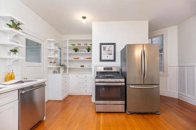 kitchen with white cabinets, stainless steel appliances, and light hardwood / wood-style flooring