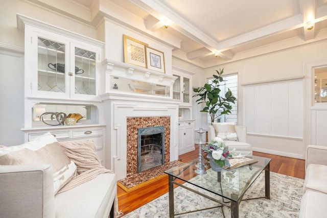 living room featuring hardwood / wood-style floors, beam ceiling, crown molding, a fireplace, and coffered ceiling