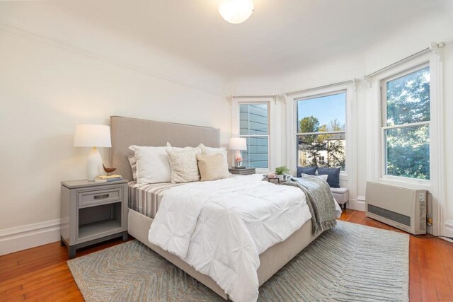 bedroom with light hardwood / wood-style flooring and heating unit