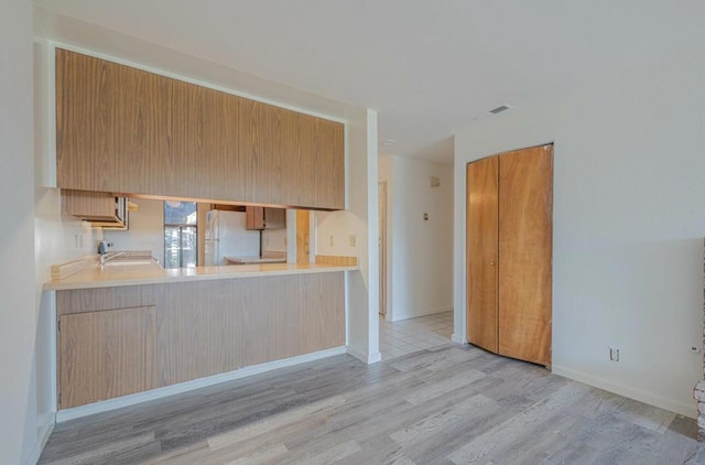 kitchen featuring sink, white refrigerator, and light hardwood / wood-style flooring