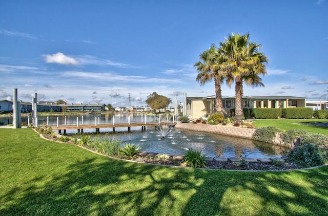 view of dock with a lawn and a water view