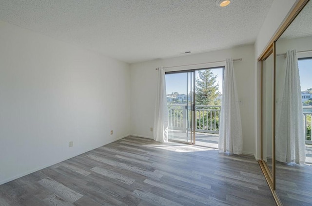 unfurnished room with hardwood / wood-style floors and a textured ceiling