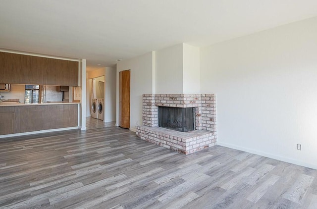 unfurnished living room with a fireplace, light hardwood / wood-style floors, and separate washer and dryer