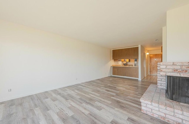 unfurnished living room with light hardwood / wood-style floors and a brick fireplace