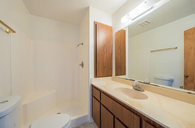 bathroom featuring toilet, a shower, and vanity