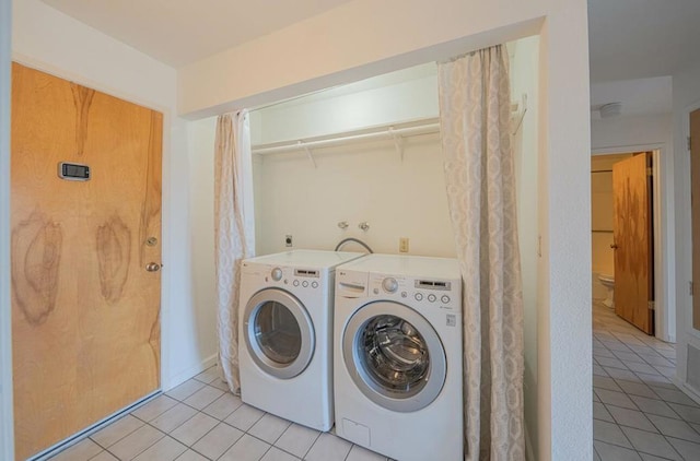 clothes washing area with washing machine and dryer and light tile patterned floors