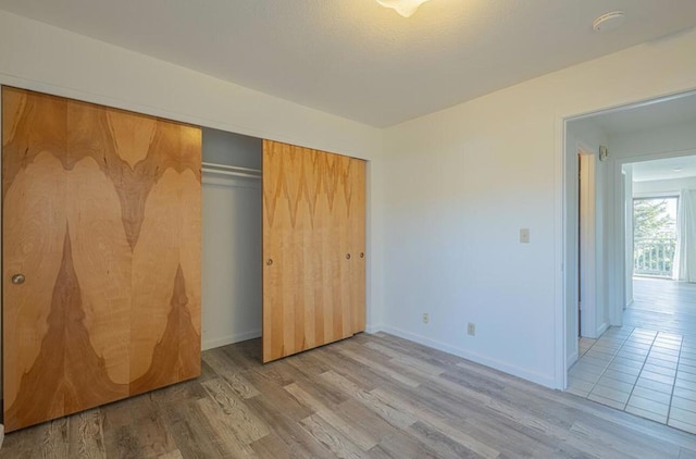 unfurnished bedroom with a closet and light wood-type flooring