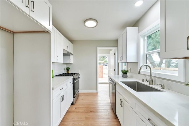 kitchen featuring sink, stainless steel appliances, white cabinets, exhaust hood, and light wood-type flooring