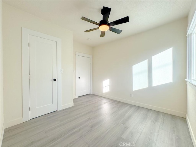 unfurnished bedroom with ceiling fan, multiple windows, and light hardwood / wood-style flooring