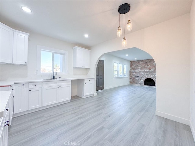 kitchen with a brick fireplace, sink, white cabinets, and a healthy amount of sunlight