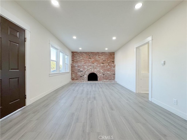 unfurnished living room with a fireplace and light hardwood / wood-style floors