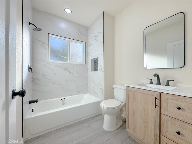 full bathroom featuring toilet, tiled shower / bath combo, hardwood / wood-style floors, and vanity