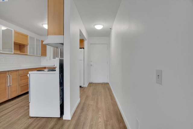 kitchen featuring white appliances, light hardwood / wood-style flooring, and tasteful backsplash