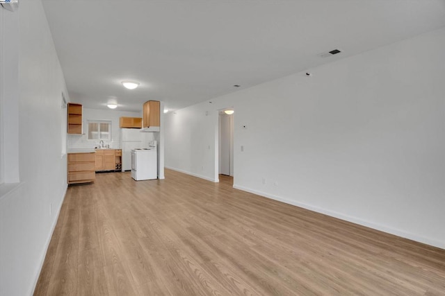 unfurnished living room featuring sink and light wood-type flooring