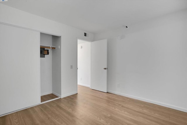 unfurnished bedroom featuring light hardwood / wood-style floors and a closet