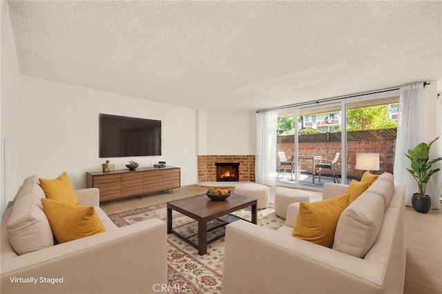 living room featuring a fireplace, a textured ceiling, and a wall of windows