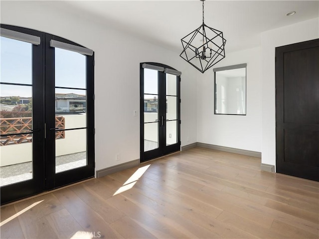 interior space with french doors, an inviting chandelier, and light wood-type flooring