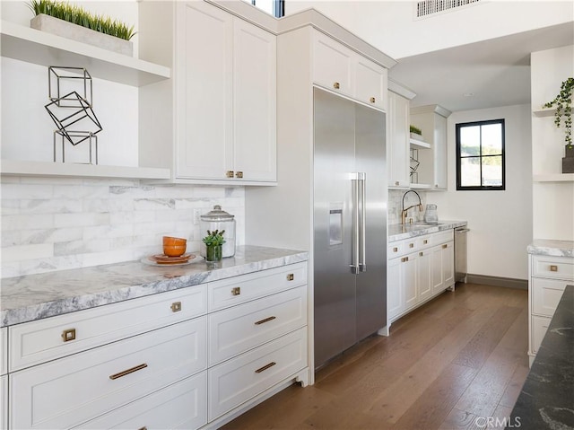 kitchen with stainless steel appliances, dark wood-type flooring, tasteful backsplash, and white cabinetry