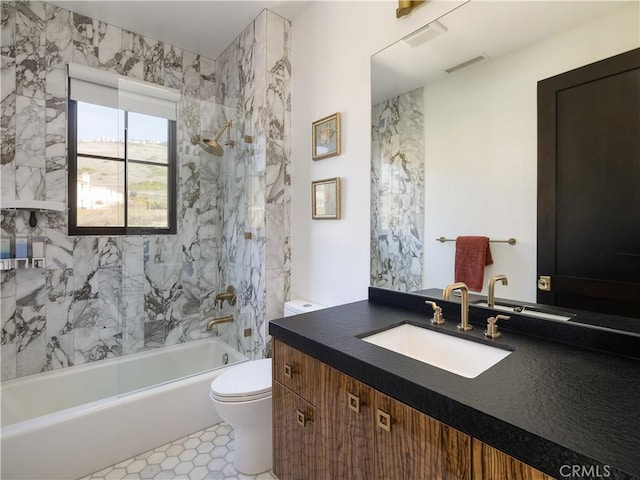 full bathroom featuring vanity, tile patterned flooring, tiled shower / bath combo, and toilet