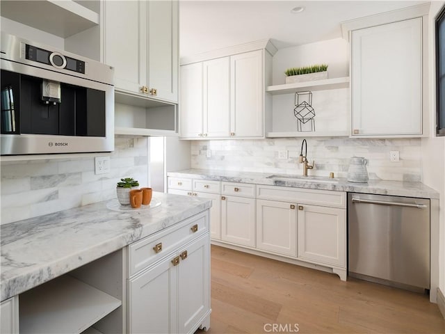 kitchen with sink, white cabinetry, dishwasher, light wood-type flooring, and light stone countertops