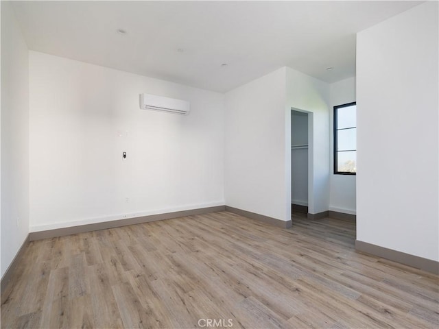 spare room featuring a wall mounted AC and light hardwood / wood-style flooring