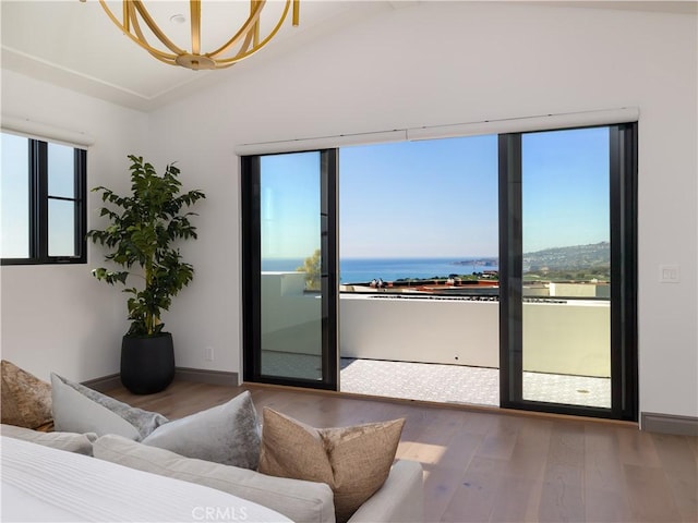 interior space featuring lofted ceiling, wood-type flooring, a chandelier, and a water view