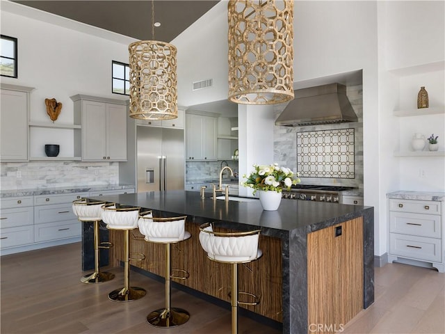 kitchen featuring sink, high vaulted ceiling, custom exhaust hood, and a kitchen breakfast bar