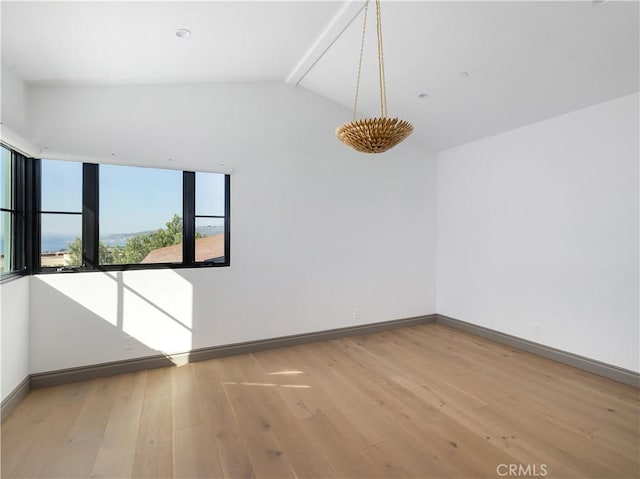 spare room with vaulted ceiling and light hardwood / wood-style flooring